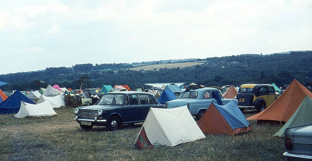 Photograph of the camping site at the 'Isle of Wight Festival' with multiple tents and cars (1969)