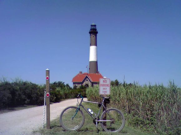 Photograph of the Fire Island lighthouse with a 'No Parking' sign and a bicycle, Long Island, New York (2007)