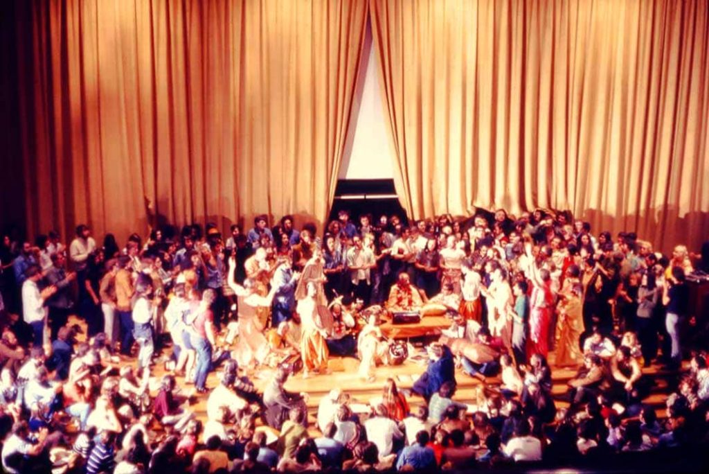 Photograph Allen Ginsberg (centre) surrounded by dozens of people at the presentation by the Swami Bhaktivedanta to support the OSU Yoga Society and local Hare Krishna held in Hitchcock Hall Auditorium, Columbus, Ohio, USA (1969)