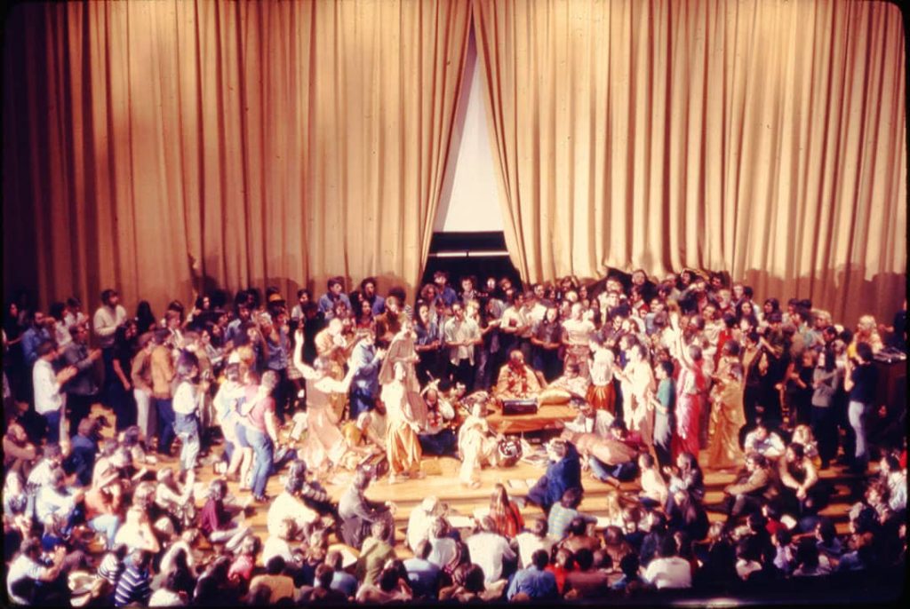 Photograph Allen Ginsberg (centre) surrounded by dozens of people at the presentation by the Swami Bhaktivedanta to support the OSU Yoga Society and local Hare Krishna held in Hitchcock Hall Auditorium, Columbus, Ohio, USA (1969)